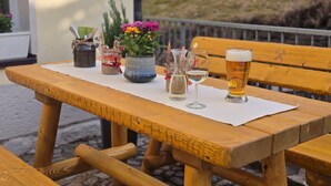 A wooden table with a white placemat, a glass of beer, a glass of white wine, and a potted plant with flowers. - Room 'Rote Pockau' with Mountain View and Wi-Fi (Marienberg OT Pobershau)