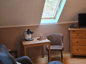 A room with a skylight, a coffee maker, a chair, a TV, and a wooden dresser. - Room 'Rote Pockau' with Mountain View and Wi-Fi (Marienberg OT Pobershau)