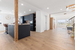 Een moderne keuken met houten vloeren, een centraal eiland en inbouwmeubels.