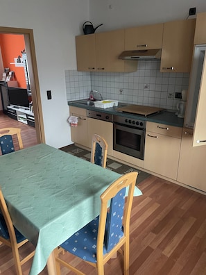 Une cuisine de taille réduite comprenant une table à manger, des chaises, une cuisinière, un four et un évier.