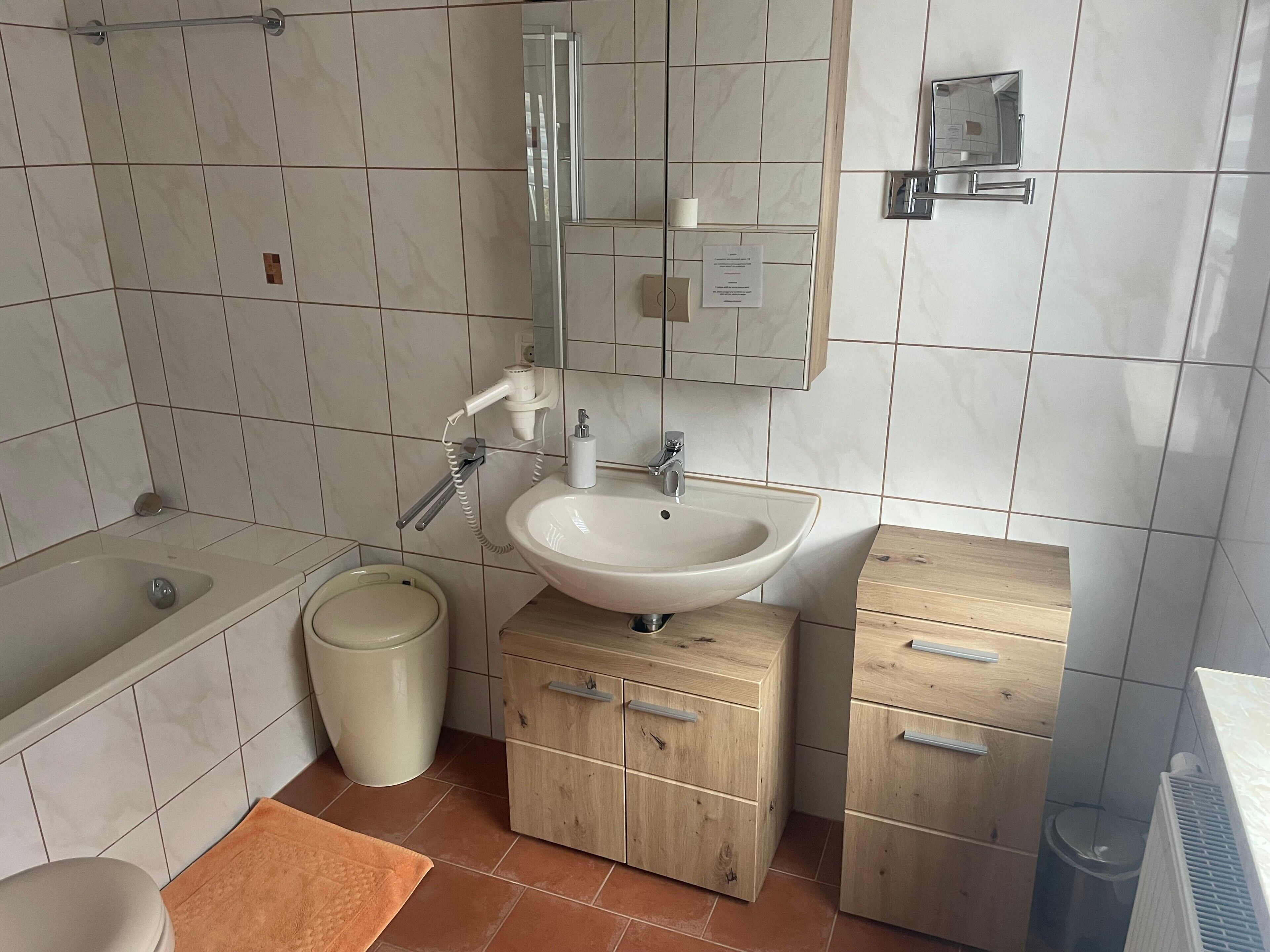 Une salle de bain avec une baignoire, un lavabo, un miroir et des meubles en bois.