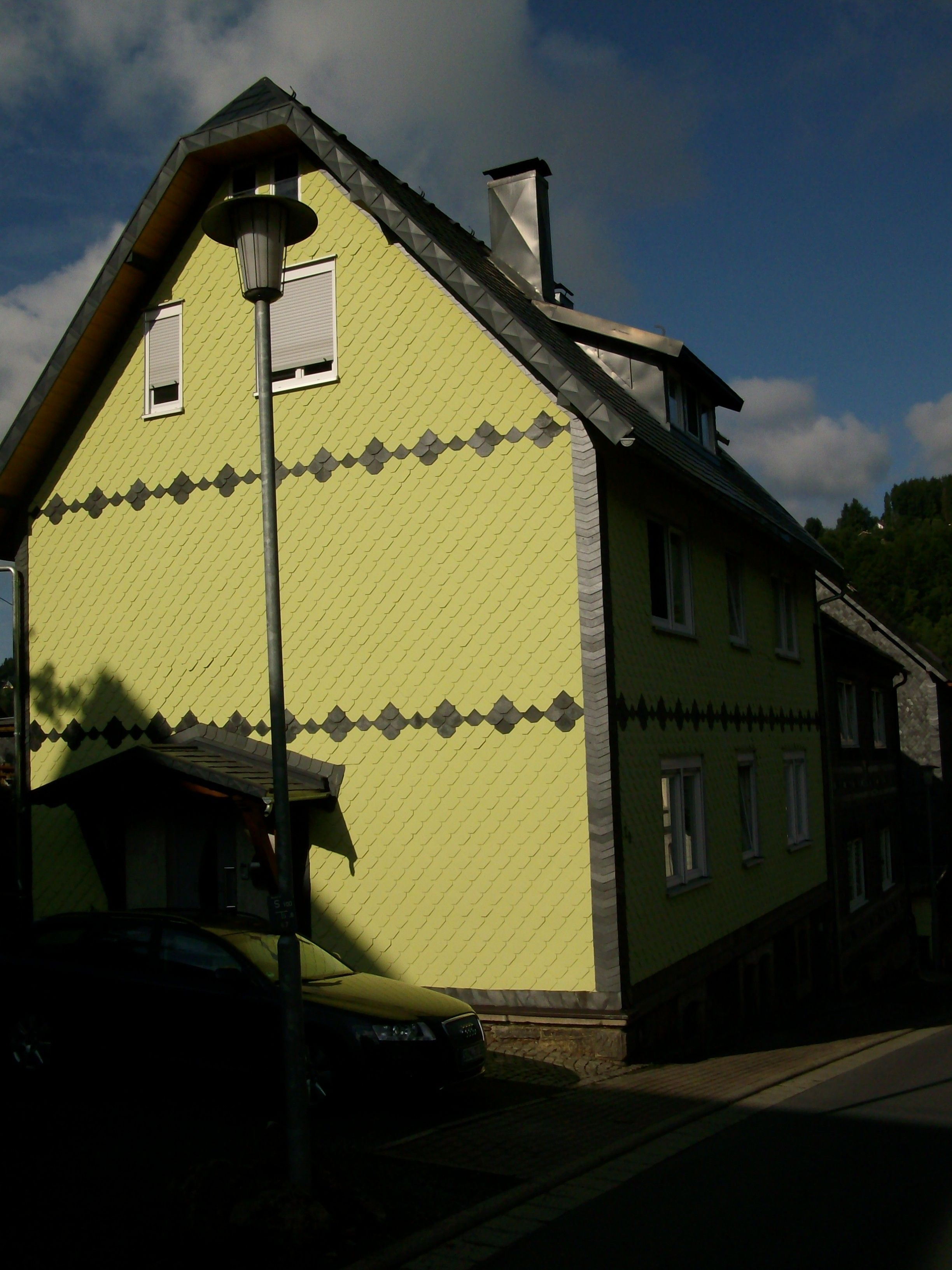 A building with a distinctive green facade and a traditional pitched roof.
