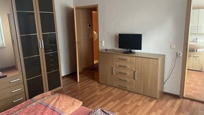 A bedroom with a bed, wardrobe, TV, and a bathroom visible through an open door.