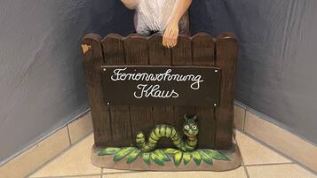 Een decoratief dierenbeeldje voor een houten hek met een bordje waarop 'Ferienwohnung Klaws' staat.