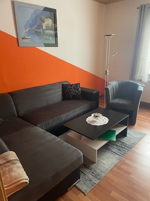 Un salon moderne avec un canapé, une table basse, une lampe sur pied et un tableau accroché au mur.