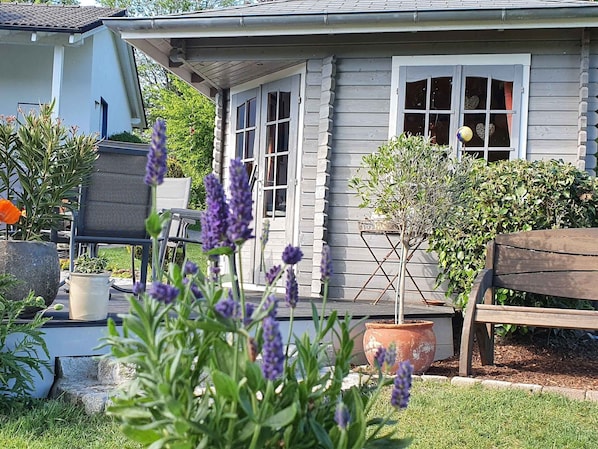 Une maison avec un porche, un banc en bois et des plantes en pot.