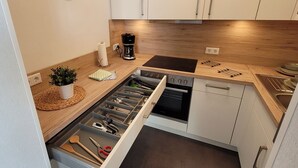 Une cuisine moderne avec des meubles en bois, un four encastré et une machine à café.