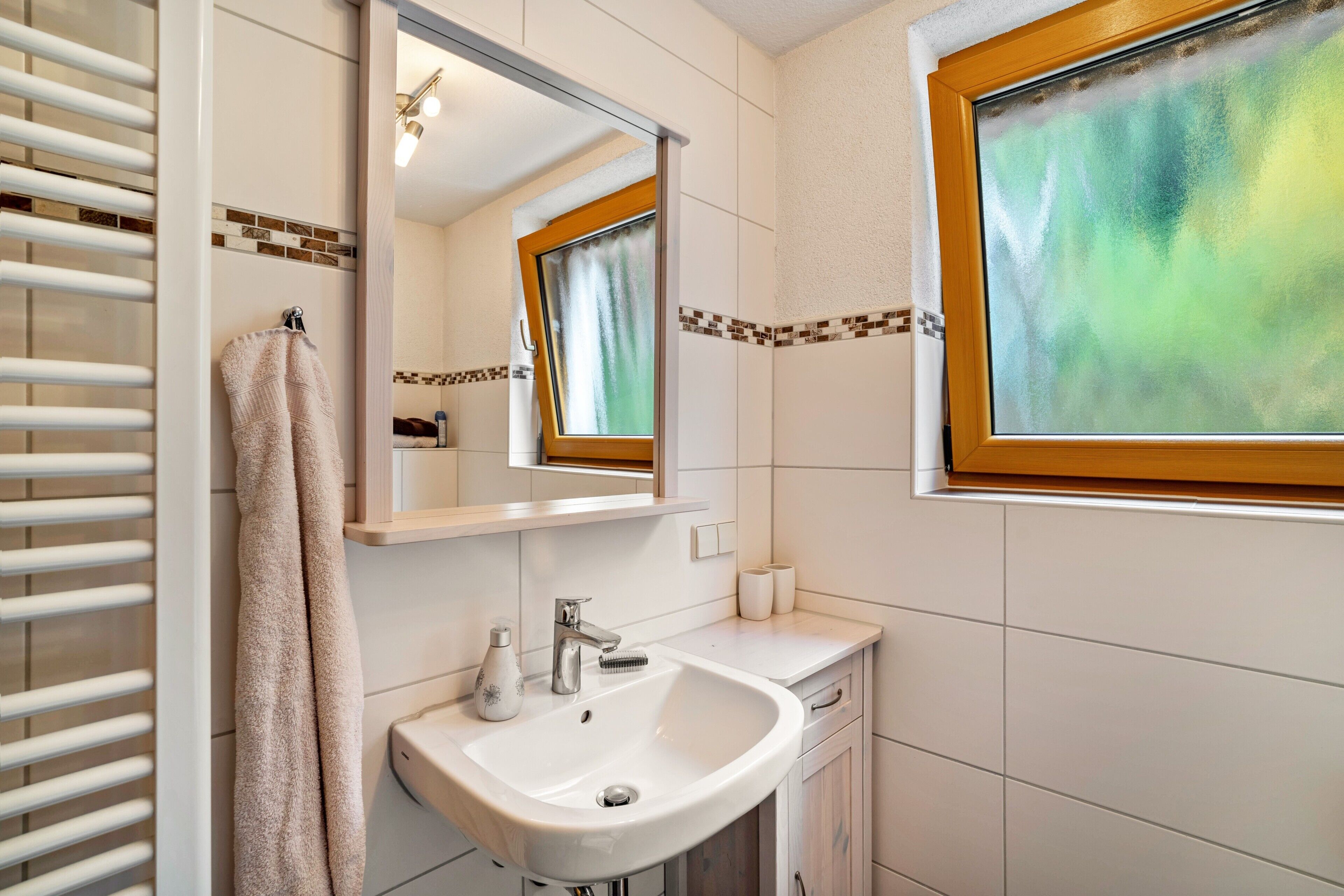 A bathroom with a white sink, mirror, towel rack, and a window with a view.
