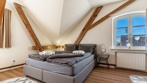 Un dormitorio con cama, ventana, radiador y vigas de madera.