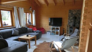 A cozy living room with a sectional sofa, a small table, a leather rug, a TV, and a fireplace. - Chalet Finkennest: Mountain Views, Private Terrace, Peaceful Location in Neukirchen (Neukirchen am Großvenediger)