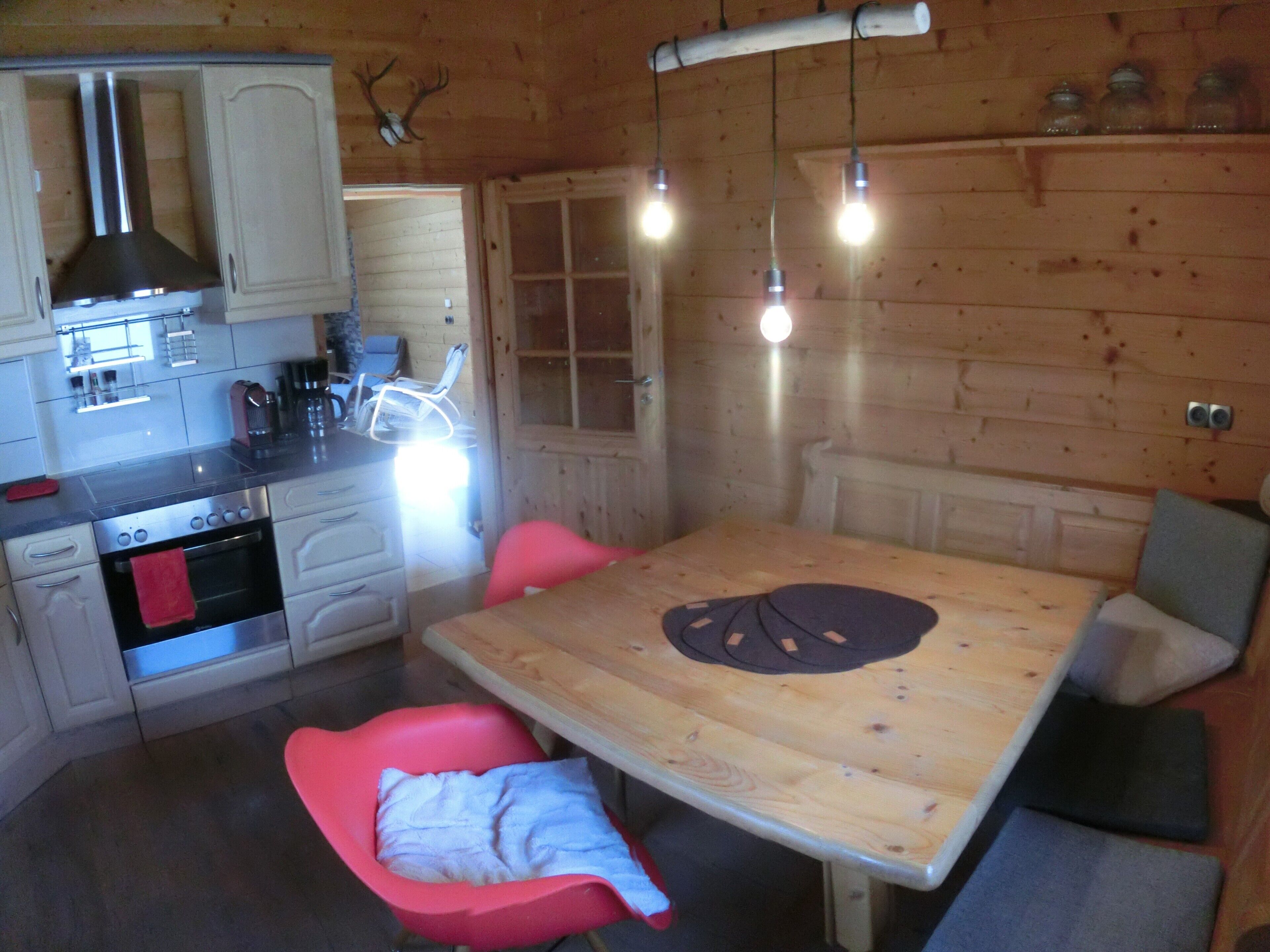 A wooden interior with a kitchen, dining table, and chairs.
