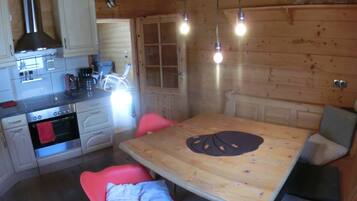 A wooden interior with a kitchen, dining table, and chairs.