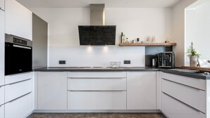 Eine moderne Küche mit weißen Schränken, einer Edelstahl-Dunstabzugshaube und einem Einbauofen.