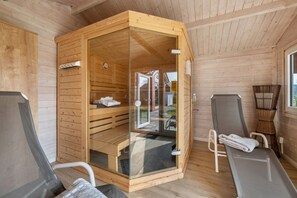 Una sala de sauna con paredes de madera, una puerta de vidrio, un banco y dos sillones reclinables.