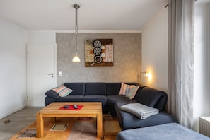 Una sala moderna con un sofá modular, una mesa de centro de madera y una obra de arte abstracta colgada en la pared.
