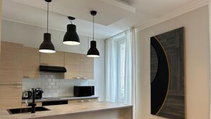 Une cuisine moderne dotée de luminaires suspendus, d’un four à micro-ondes et d’un évier.