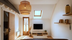 Un salon moderne avec un téléviseur, des meubles en bois, une grande fenêtre et un luminaire au plafond.