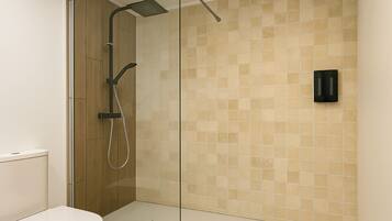 A modern bathroom with a glass shower enclosure, a toilet, and a tiled wall.