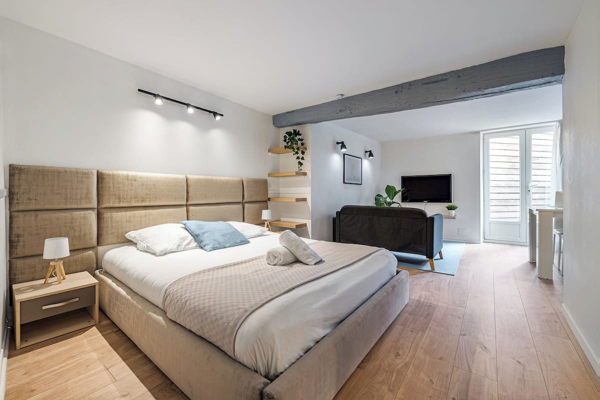 Ein Schlafzimmer mit einem großen Bett, Nachttischen, einem Fernseher und einer Pflanze.