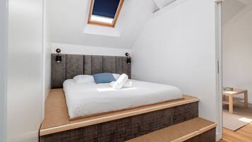 A bedroom with a bed, a small table, and a window.
