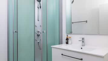 A modern bathroom with a glass-enclosed shower, a white sink, and a mirror above it.