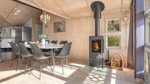 Eine moderne Küche mit einer zentralen Kochinsel, einem Essbereich mit Stühlen, einer Chandelierleuchtre und einem Holzofen.