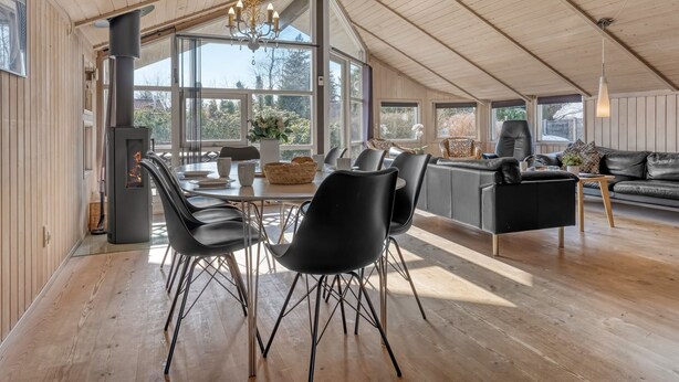 Ein geräumiges Loft mit hoher Decke, großen Fenstern, einem Essbereich mit modernen Stühlen, einem schwarzen Ledersofa und einem Kamin.
