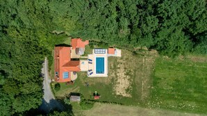 Eine Vogelperspektive eines Hauses mit Schwimmbad, umgeben von dichtem Wald.