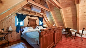 Una camera da letto mansardata accogliente con un letto di legno, una scrivania e una sedia.