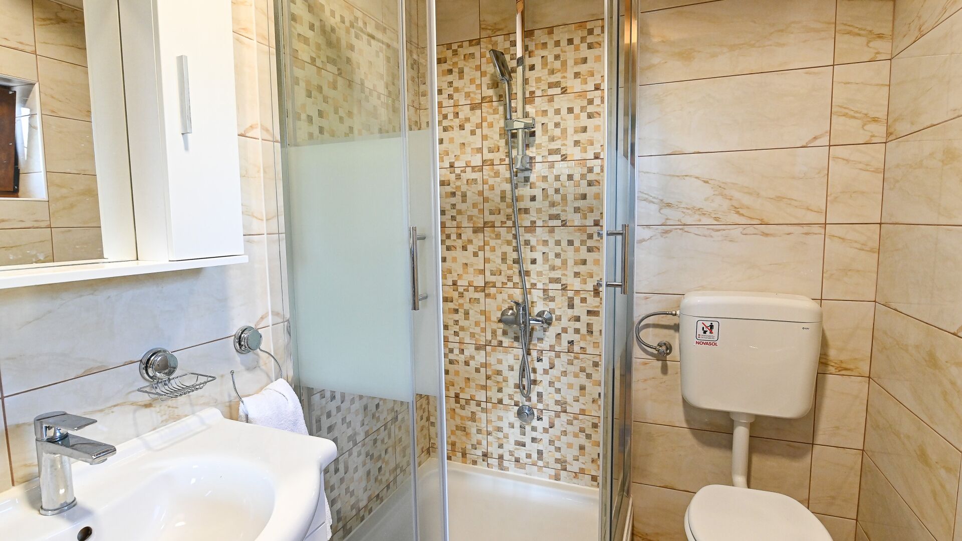 Une salle de bain avec douche, toilettes, lavabo et un mur carrelé.