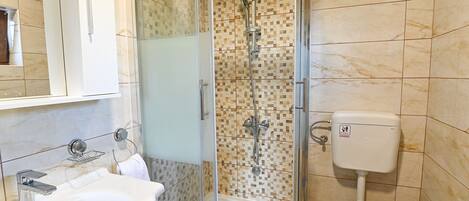 Une salle de bain avec douche, toilettes, lavabo et un mur carrelé.
