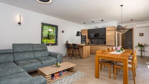 Un salon moderne avec un canapé gris, une table basse en bois et un coin repas comprenant une table et des chaises en bois.
