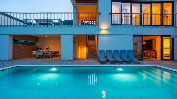 Une maison moderne à deux étages, dotée d’une piscine, d’un espace salon ext érieur et d’un escalier menant à l’étage supérieur.