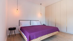 Um quarto com cama, mesa de cabeceira e guarda-roupa.