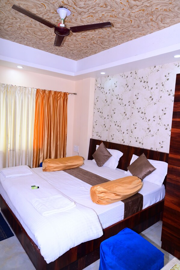 A double bed with a wooden headboard, a ceiling fan, and a floral-patterned wall.