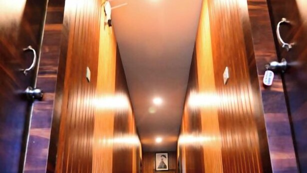 A corridor with wooden paneling and a marble floor leading to a door. - DhamStay Hotel Aradhya Near Beach Puri  (Puri)