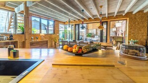 A spacious kitchen with wooden beams, a fruit bowl on the counter, and a view of the outdoors. - Exceptional urban loft with swimming pool: the ideal address for a dream vacation. (Brive-la-Gaillarde)