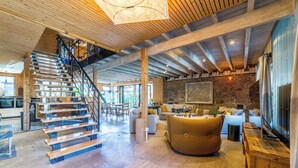 A spacious living area with a wooden staircase, a large sofa, and a stone wall. - Exceptional urban loft with swimming pool: the ideal address for a dream vacation. (Brive-la-Gaillarde)