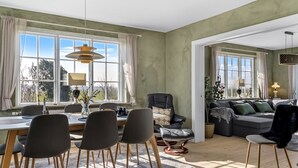 Una sala de estar moderna con comedor, ventanas amplias y vistas al exterior.