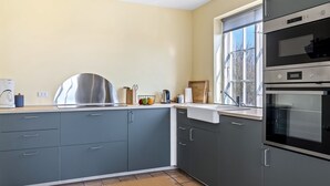 Una cocina moderna con armarios grises, electrodomésticos de acero inoxidable y un ventanal amplio.
