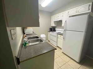 A compact kitchen with white cabinets, a built-in oven, a refrigerator, and a sink with a countertop. - Private 1 Bedroom Apartment in Lawton near Fort Sill (Lawton)
