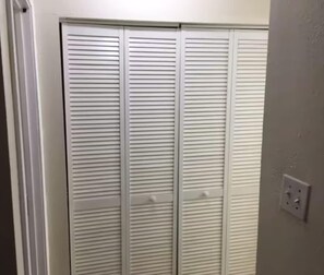 A white closet with horizontal louvered doors and a light switch on the wall. - Private 1 Bedroom Apartment in Lawton near Fort Sill (Lawton)