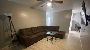 A living room with a sectional sofa, a coffee table, a floor lamp, and a ceiling fan.