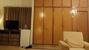 Une chambre équipée d’une armoire, d’une télévision, d’un petit réfrigérateur et d’une chaise.