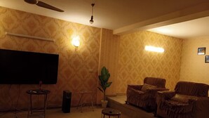 Un salon équipé d’un téléviseur à écran plat, de deux canapés, d  ’une table basse, d’une plante et d’un ventilateur de plafond.