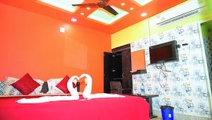 A hotel room with a bed, a ceiling fan, a TV, and a wall with a circuit board design. - DhamStay Hotel Ashoka Royal Near Beach (Puri)