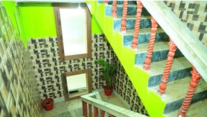 A staircase with a checkered tile wall, a potted plant, and a window. - DhamStay Hotel Ashoka Royal Near Beach (Puri)