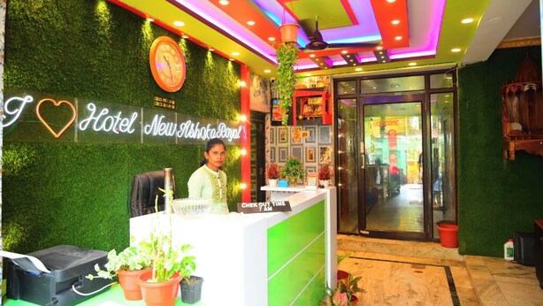 A hotel reception desk with a green wall, a clock, and a sign that reads "I ♥ Hotel New Mshoka Royal". - DhamStay Hotel Ashoka Royal Near Beach (Puri)