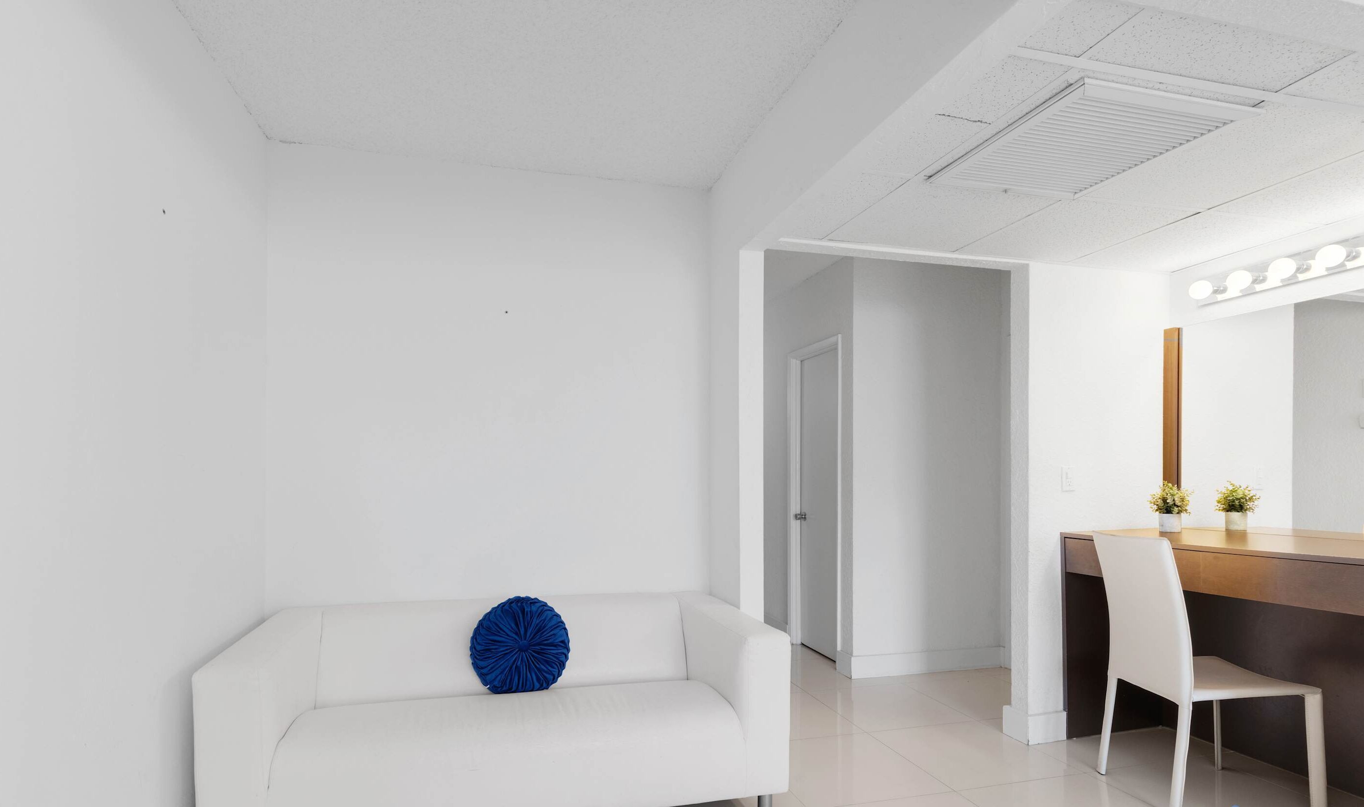 Ein modernes, minimalistisches Zimmer mit einem weißen Sofa, einem Holztisch und einem weißen Stuhl.
