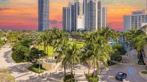 A modern urban area with high-rise buildings, palm trees, and a well-maintained road. - 2BR 2BTH - Apartment  - Free Parking (Sunny Isles Beach)